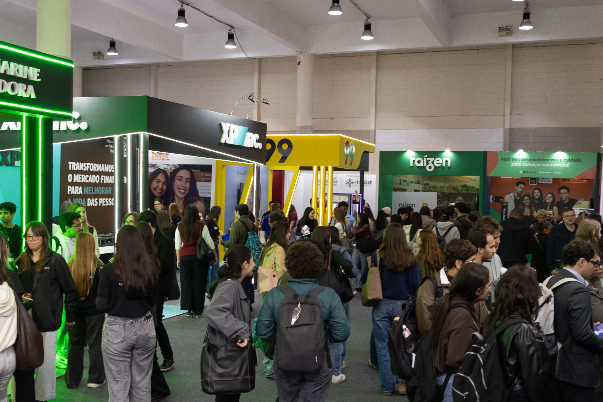 Corredor da feira da Semana de Recrutamento, com estandes de empresas e estudantes circulando